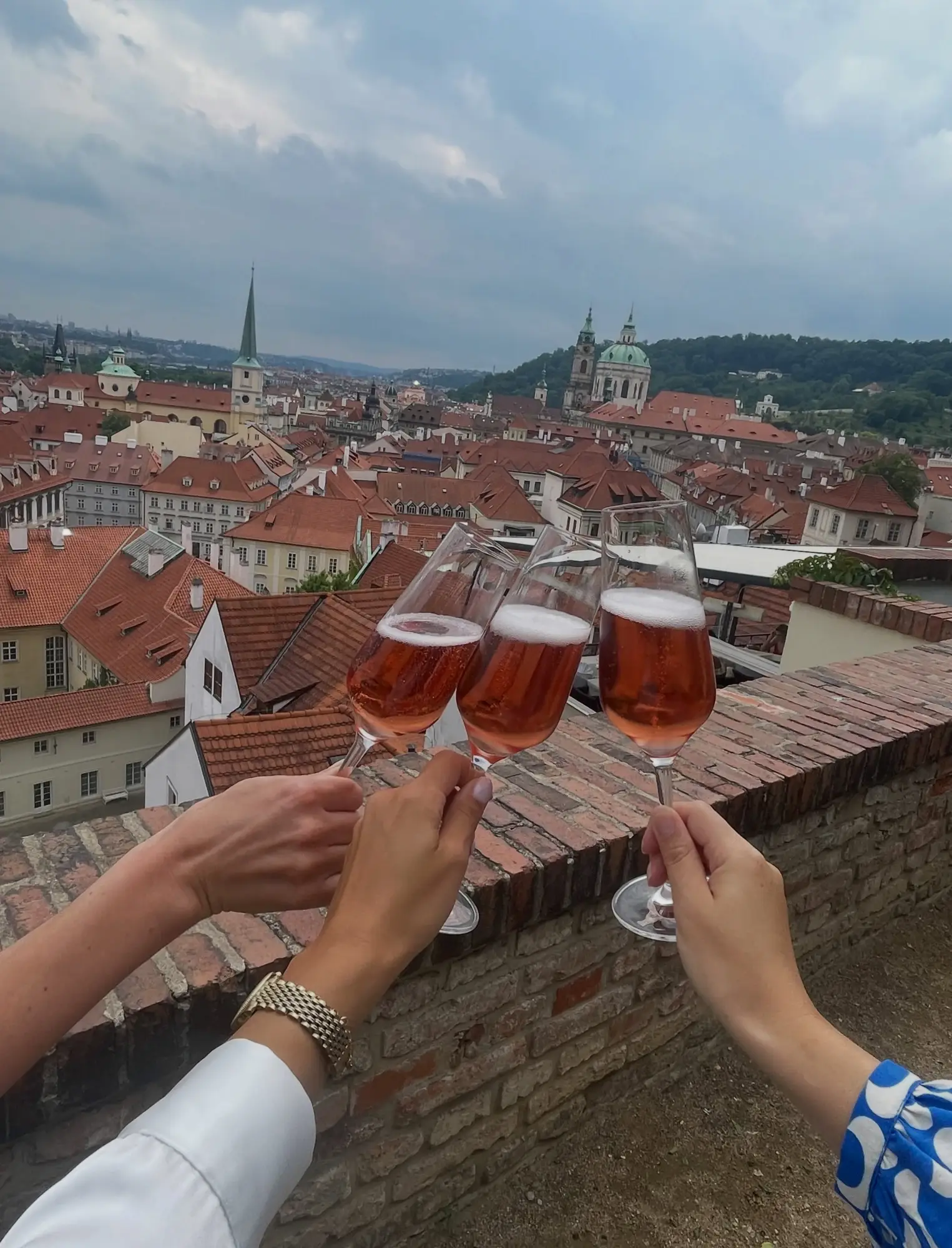 A toast with rosé champagne above the rooftops of Prague at Terasa U Zlaté studně